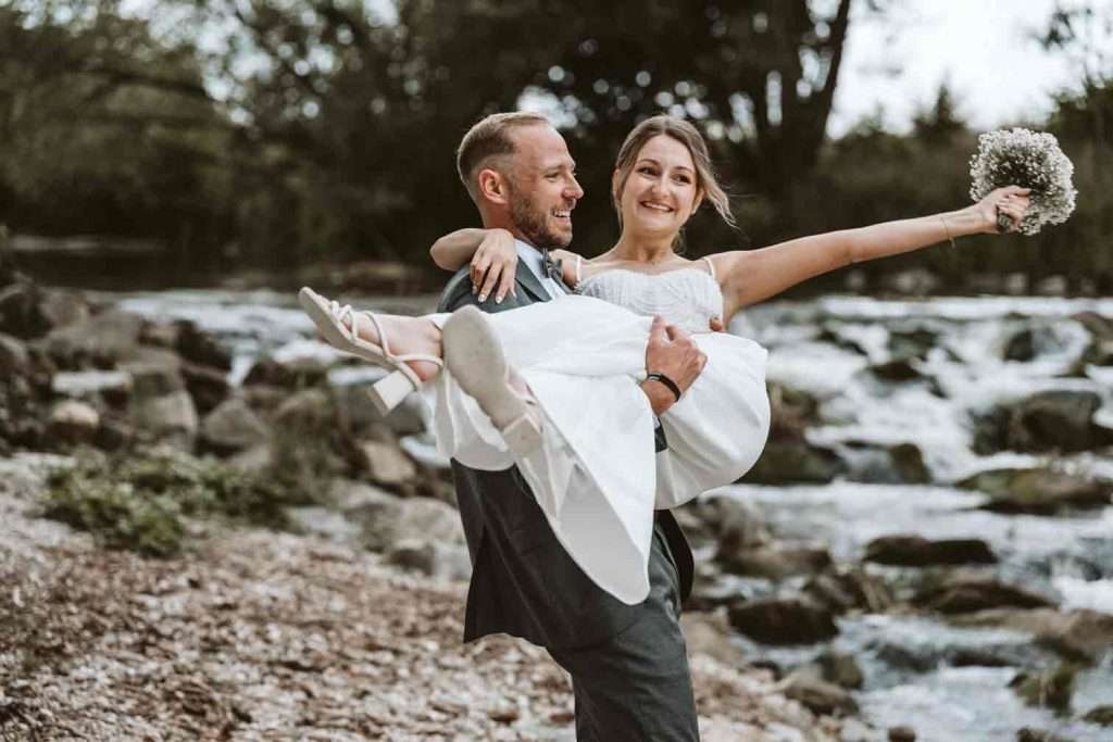 Bräutigam trägt Braut beim Brautpaarshooting